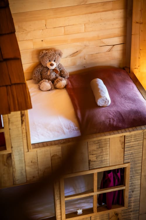 Gezellig houten stapelbed in de Mayreau-kamer van Domaine De Campagnac, Carsac-Aillac, met teddybeer en bordeauxrood beddengoed