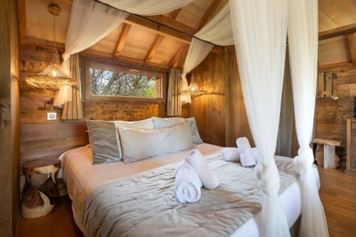 Luxe slaapkamer met houten hemelbed, witte sheer gordijnen en tuinzicht in Domaine De Campagnac in Carsac-Aillac