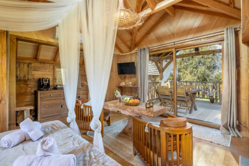 Luxe houten bungalowslaapkamer bij Domaine De Campagnac met hemelbed, tuinuitzicht en moderne voorzieningen