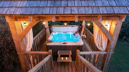 Luxueus bubbelbad op houten terras bij Domaine De Campagnac, Carsac-Aillac, met verlichte pergola en tuinuitzicht