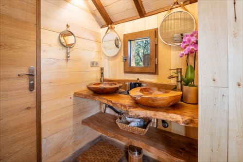 Rustic wooden bathroom at Domaine De Campagnac with dual wooden vessel sinks, round mirrors, and natural wood accents