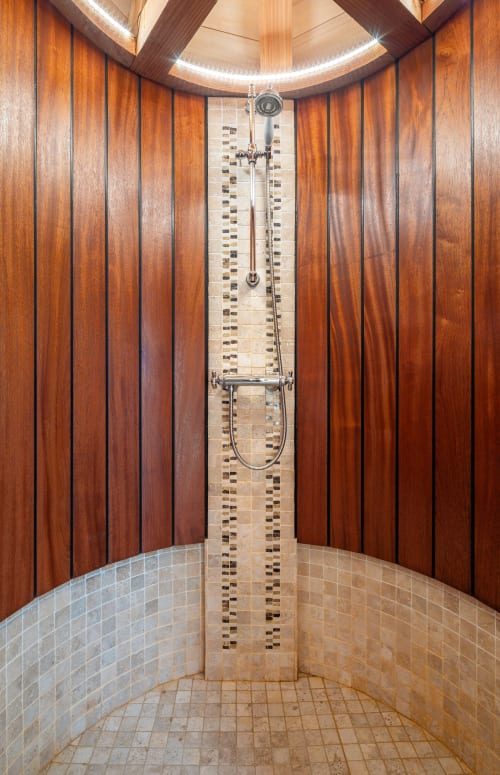 Luxury shower in Béquia room at Domaine De Campagnac, featuring warm wood paneling and modern tile accents