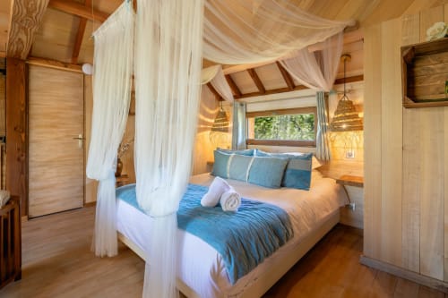 Béquia room at Domaine De Campagnac with four-poster canopy bed, blue bedding, wooden beams, and garden view window