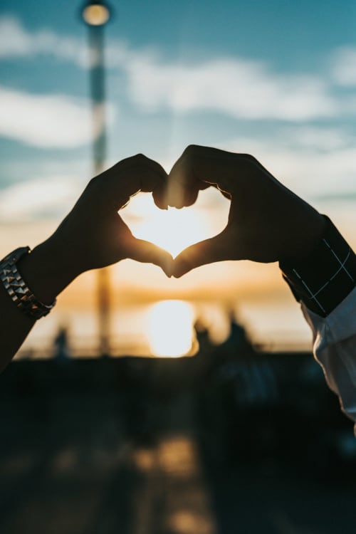 Couple formant un cœur avec les mains au coucher de soleil près du phare de la Loire, escapade romantique