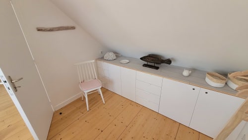 Chambre mansardée avec rangements blancs, fauteuil rose, parquet et décoration côtière à la maison d'hôtes Loc'Maria Belle île en mer.
