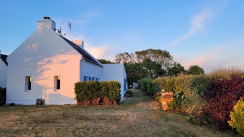 Petite maison blanche avec vue sur le jardin à Belle Île en Mer, offrant un espace de détente et salle à manger près des plages de Port Jean