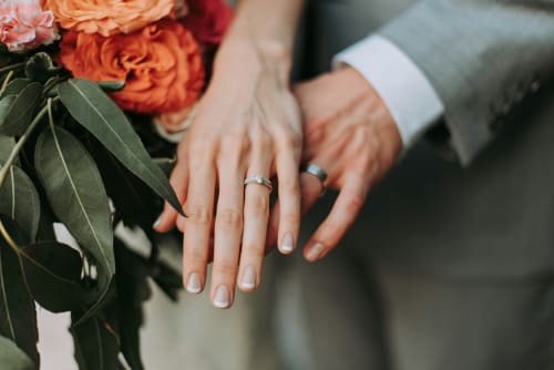 Newlyweds displaying wedding rings and bouquet at Domaine de Blanvatel, a charming bed and breakfast in Saint Pierre en Auge,