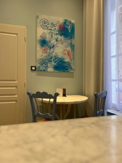 Dining area at Mes à Moi Pézenas with round table, blue chairs, and nautical-themed artwork