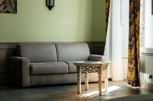 Modern living room at Mes à Moi Pézenas with gray sofa, ornate side table, and yellow patterned curtains in Pézenas, FR