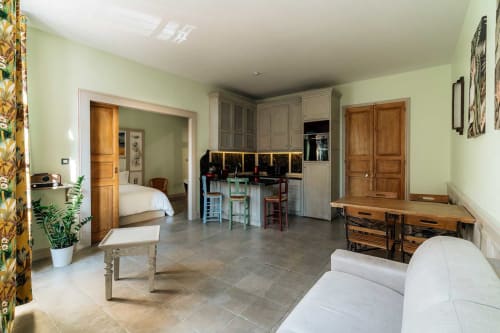 Spacious studio at Mes à Moi Pézenas featuring green walls, kitchen area, wooden furniture, and bed in Pézenas