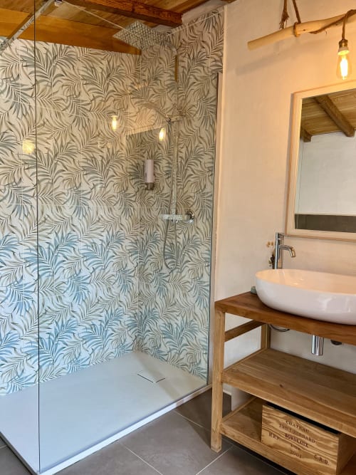 Salle de bains moderne aux carreaux patterinés, douche vitrée, vasque blanche sur meuble en bois à l'Agritusmo Stecadò à Dolceacqua