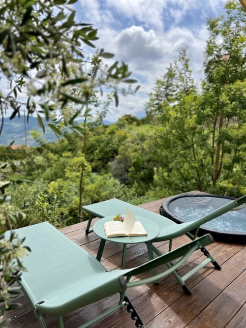 Chaises longues vert menthe sur terrasse en bois dominant une vallée luxuriante à l'Agritusmo Stecadò à Dolceacqua, Italie