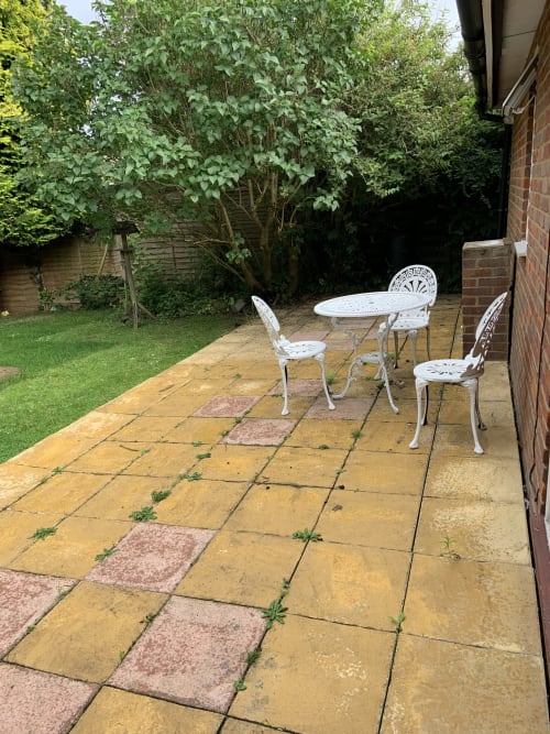 Patio seating area in a High Wycombe bungalow garden with white ornamental furniture and lush green plants