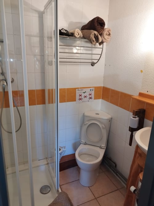 Bathroom at L'étape Du Fanfoué with white toilet, shower cabin, and orange tile accents, Chamrousse