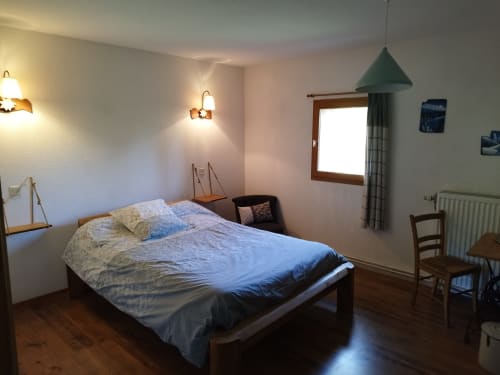 Cozy bedroom at L'étape Du Fanfoué in Chamrousse with wooden bed, warm lighting, and mountain view window