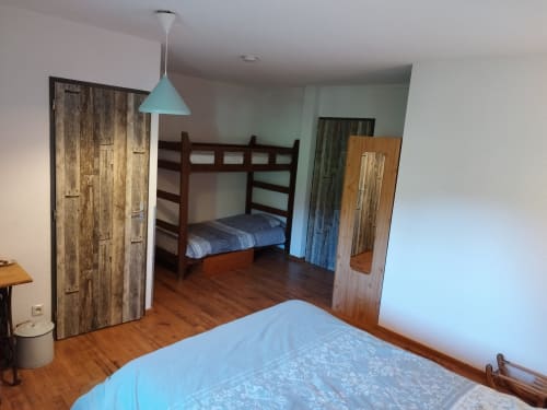 Spacious bedroom at L'étape Du Fanfoué in Chamrousse with bunk bed, hardwood floors, and turquoise pendant light