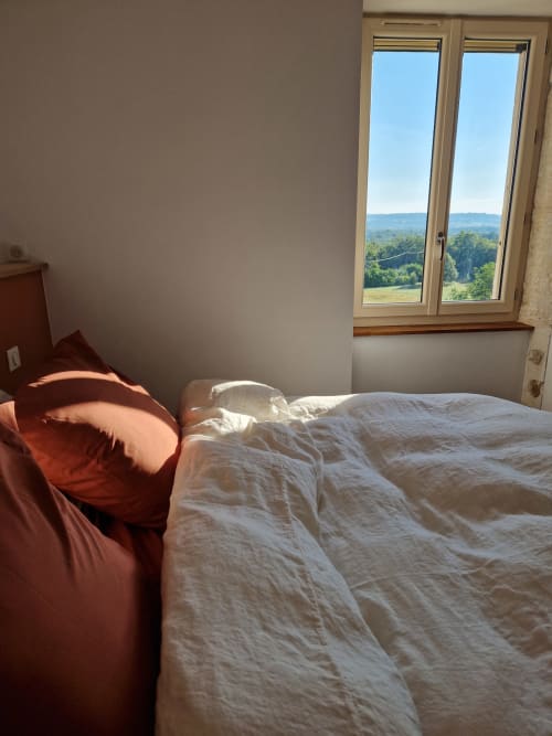 Chambre lumineuse de la Maisonaurinko B&B avec vue sur le jardin par portes-fenêtres dominant la campagne de Thenon