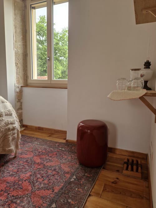 Chambre accueillante à la Maisonaurinko B&B à Thenon avec vue sur le jardin, ottoman bordeaux, étagères en bois et décor rustique
