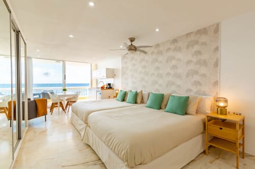 Modern beachfront hotel room in Arguineguín with ocean views, twin beds, green accents, and coastal décor