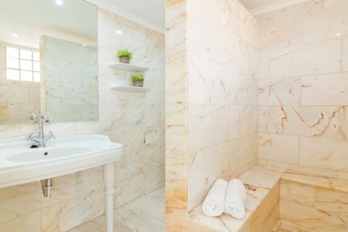 Luxury marble bathroom with vanity sink, mirror, shelving, and rainfall shower area at Sunset ocean view hotel in Arguineguín