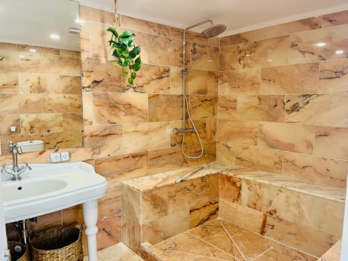Luxury bathroom with marble tile walls, walk-in shower, and pedestal sink at Sunset ocean view hotel in Arguineguín