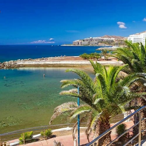 Sunset Ocean View hotel in Arguineguín with palm trees, beach cove, and turquoise Mediterranean waters