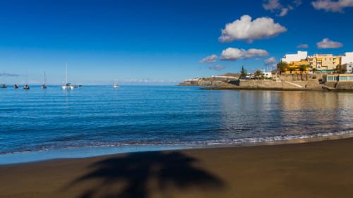 Arguineguín-Strand mit Segelbooten, goldenen Gebäuden und kristallklarem Meerwasser bei Sonnenuntergang