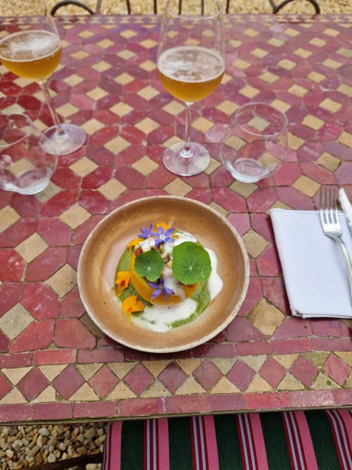 Assiette élégante chez Maisonaurinko à Thénon - cuisine raffinée avec fleurs comestibles et jeunes pousses sur bol en céramique