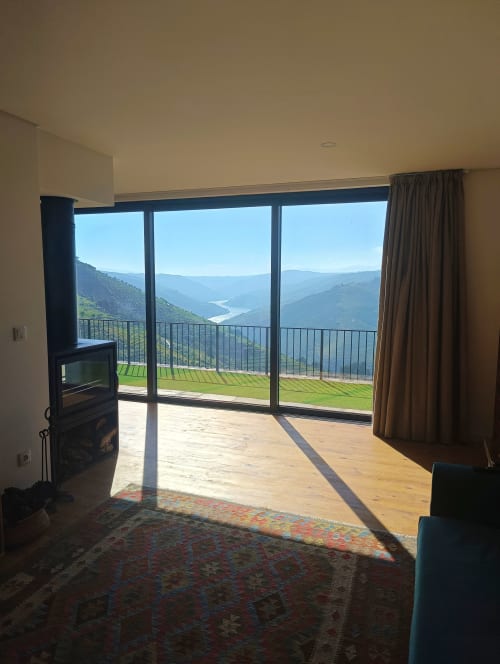 Interior de casa rural no Vale do Douro com vistas panorâmicas do rio através de janelas do chão ao teto, terraço de madeira e montanha