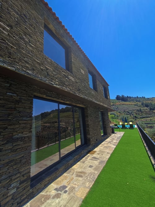 Terraço de pedra moderno na Quinta do Fraguil com vista para os vinhedos do Vale do Douro, jardim verde e paisagem montanhosa