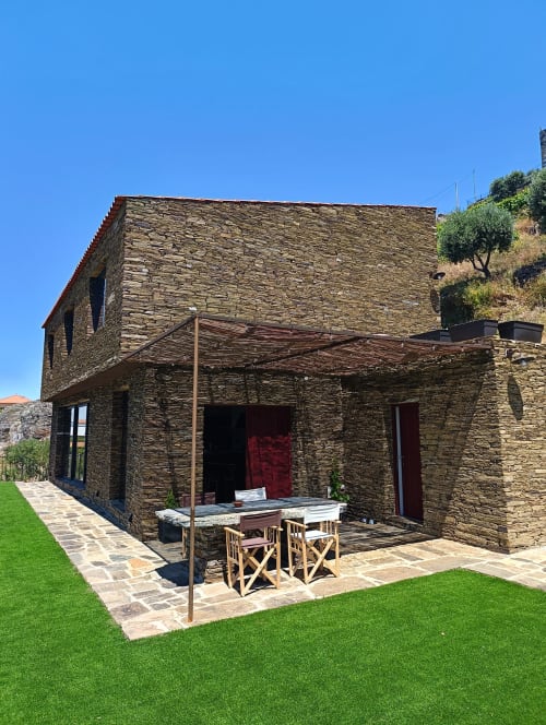 Casarão de pedra na Quinta do Fraguil, Douro, com terraço, zona de refeições e jardim impecável sob céu limpo