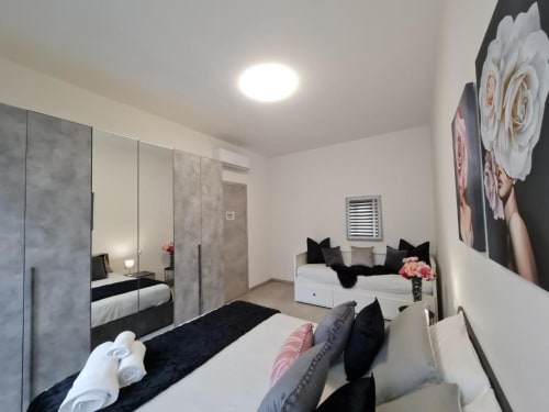 Moderna spavaća soba u Raymihome Turin apartmanu s ogledalom ormarom, bijelim posteljinama, crnim akcentima i cvjetnim zidnim umjetnostima