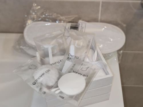 Hotelske pogodnosti raspoređene na umivaonom bloku kupaonskog apartmana Raymihome Turin, uključujući dentalnu garnituru, kadu za tuširanje i set za toaletu