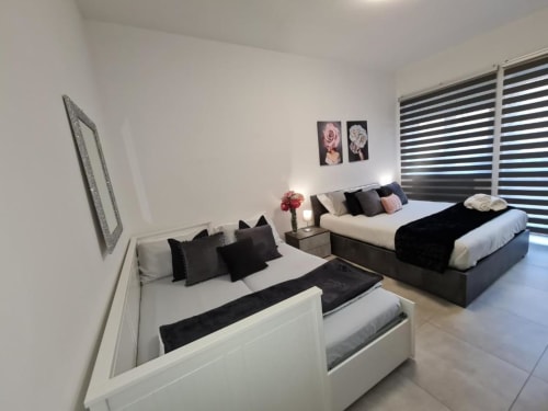 Moderan bedroom u apartmanu Raymihome Turin sa dva kreveta, crno-belom posteljinom, odeljenjem za sedenje i prugastim roletama