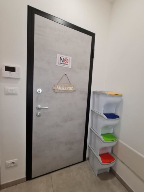 Ulazak u Raymihome apartman u Torinu s pozdravnom pločom, znakom zabranu pušenja i vrećama za reciklažu kodiranim po boji u hodniku