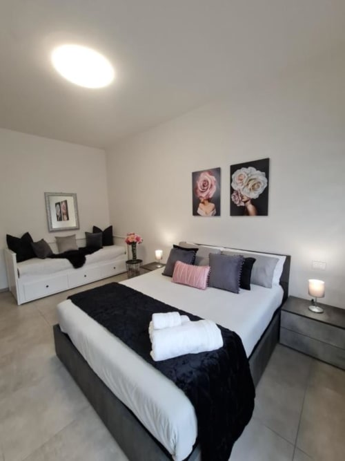 Camera da letto moderna nell'appartamento Raymihome a Torino con letto queen, zona salotto, arte floreale a parete e arredamento contemporaneo