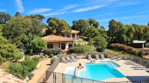 Villas Lantana pool area in Lecci with turquoise swimming pool, terracotta villa, lounge chairs, and surrounding oak trees