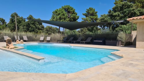 Resort swimming pool at Villas Lantana in Lecci with sun loungers, black shade sail, and Mediterranean landscaping