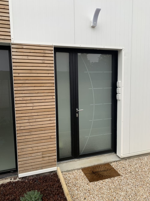 Entrée moderne de la Maison Blanche B&B à Bouguenais avec porte vitrée et panneau d'accent en bois