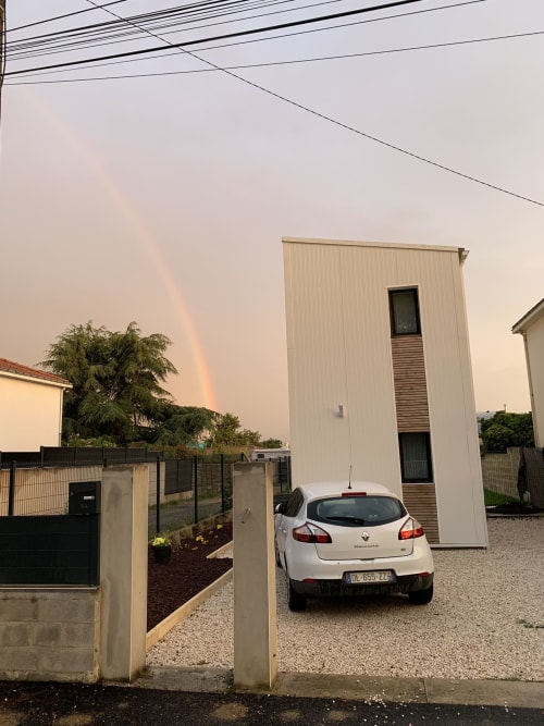 Renault blanche garée à La Maison Blanche B&B à Bouguenais, France, avec arc-en-ciel après la pluie