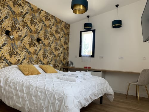 Chambre moderne à La Maison Blanche B&B à Bouguenais avec tête de lit dorée, literie blanche et luminaires noirs