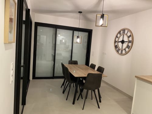 Salle à manger contemporaine à La Maison Blanche, Bouguenais : table en bois, chaises noires, horloge romaine