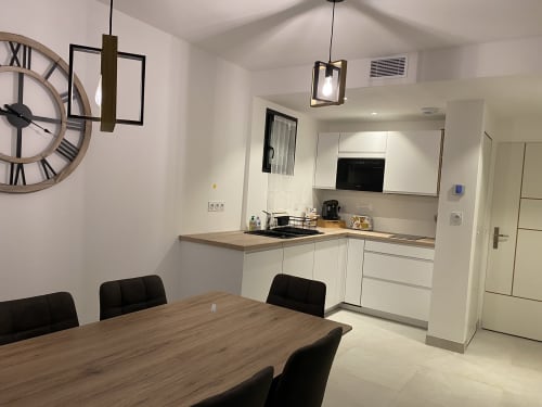 Cuisine moderne et salle à manger de la Maison Blanche B&B à Bouguenais avec armoires blanches et table en bois