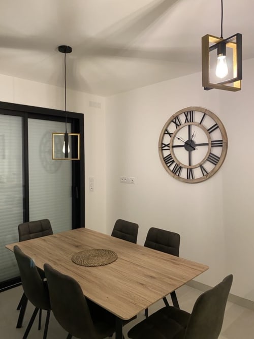 Salle à manger moderne de la Maison Blanche B&B à Bouguenais avec table en bois, chaises noires et horloge murale en chiffres romains