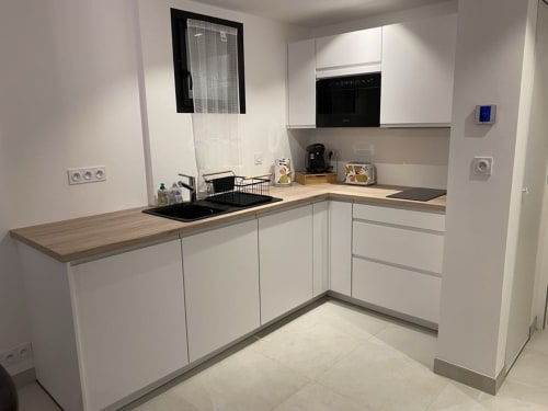 Cuisine moderne en L blanche à La Maison Blanche B&B à Bouguenais, avec plans de travail en bois et évier noir