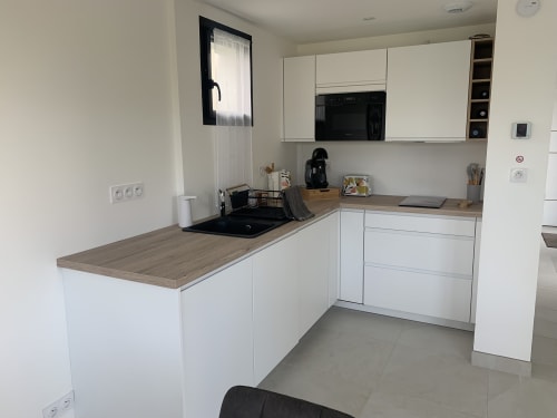 Cuisine moderne blanche à La Maison Blanche B&B à Bouguenais avec plans de travail en bois et électroménagers noirs