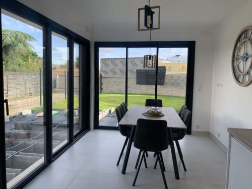 Salle à manger contemporaine avec portes vitrées à cadre noir donnant sur le jardin du Gîte La Maison Blanche, Bouguenais