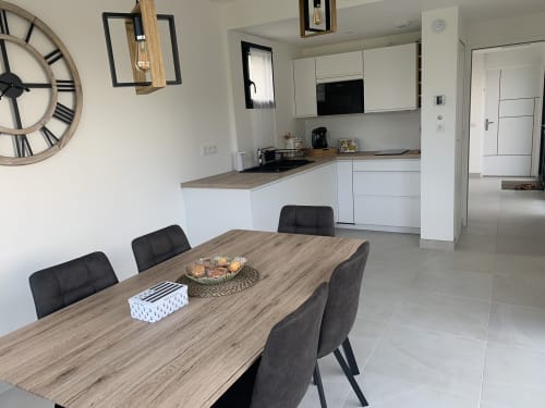 Cuisine ouverte moderne et salle à manger de La Maison Blanche B&B à Bouguenais avec table en bois et chaises noires