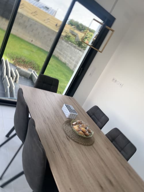 Table de salle à manger à La Maison Blanche à Bouguenais avec panier et vue sur la verdure à travers les grandes baies vitrées