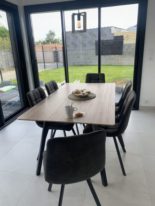 Salle à manger moderne à La Maison Blanche avec table, chaises noires, suspension et vue sur le jardin à Bouguenais